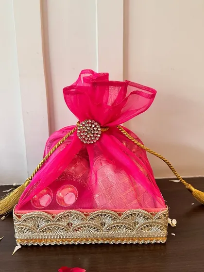 For a bold and beautiful statement, this rani pink Rakhi hamper is perfect. The rich color, combined with the elegant organza wrapping and traditional gota patti tray, makes it a truly special gift for a sibling.