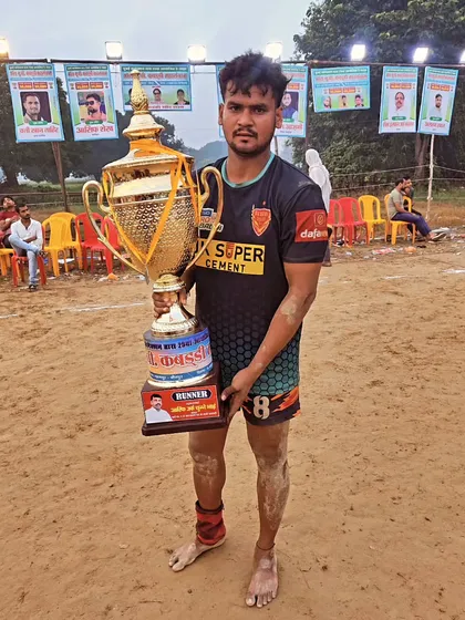 A player holding the runner-up trophy after a tough battle in a mud kabaddi tournament.