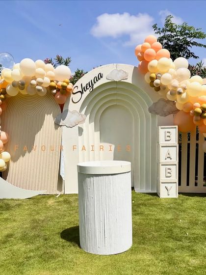 An outdoor setup for Sheyaa's baby brunch, featuring a moon-shaped backdrop and a cloud of pastel balloons. The 'BABY' blocks and teddy bear details add a sweet touch.