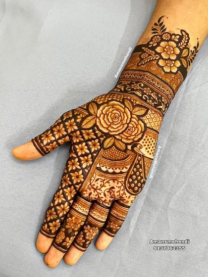 A close-up of a floral mehndi design. The large rose on the back of the hand is surrounded by a dense pattern of smaller flowers, creating a beautiful and feminine look.