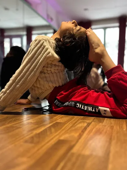 An advanced student demonstrates a beautiful scorpion pose, touching her foot to her head. This level of flexibility requires dedication, patience, and expert guidance.