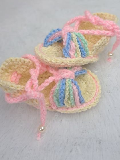 These pastel-colored gladiator-style baby sandals are so unique, with a rainbow-colored bow and soft pink laces.