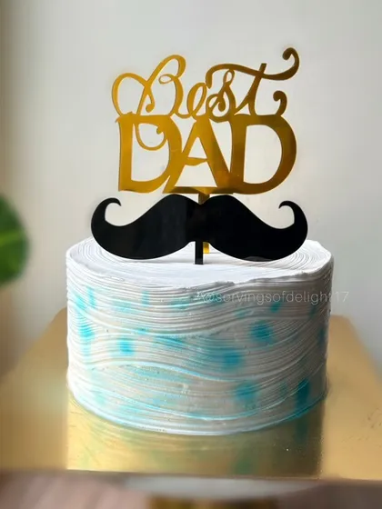A cake for the "Best Dad," featuring a textured blue and white design and a classic mustache topper. A perfect treat for Father's Day.