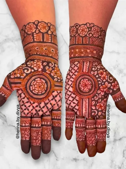 A beautiful symmetrical Indian mehendi with a central floral mandala and a grid pattern on the palms. The wrists feature a classic band of roses.