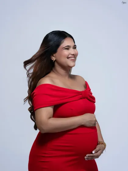 A radiant solo portrait of the mother-to-be. The wind in her hair and her joyful smile capture the beautiful energy of pregnancy. A simple white background keeps the focus entirely on her glow.