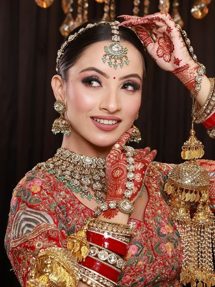 A beautiful bride looking away with a smile, her mehandi-adorned hands holding her kalire, a classic bridal moment.