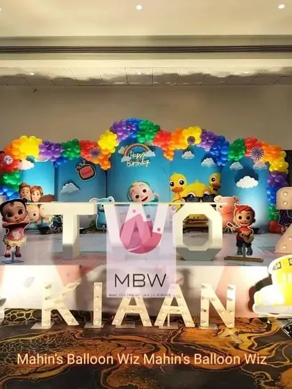 A grand Cocomelon "TWO" cool party for a second birthday. The setup includes large marquee letters, a rainbow balloon arch, and all the favorite characters ready to celebrate.