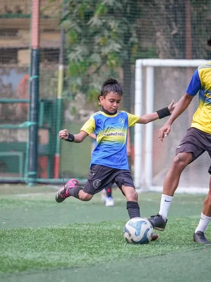 A coach gently guides a very young player during a drill, demonstrating a tackle. This heartwarming shot shows our commitment to helping our youngest players fall in love with the game.