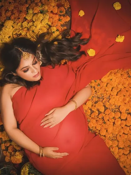 Dreaming in a sea of flowers. This overhead shot captures a peaceful moment, with the mother-to-be resting on a bed of marigolds, her red drape creating a beautiful contrast.