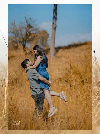A playful lift during their outdoor pre-wedding shoot. This photo is full of joy and natural interaction, capturing the fun side of their relationship against a beautiful, sunlit natural backdrop.