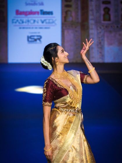 Actress Radhika Narayan gracing the runway in a stunning golden saree. This shot captures her elegant pose, showcasing the traditional jewelry and the richness of the garment for the brand.