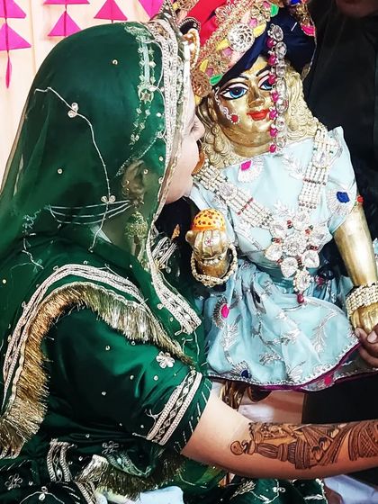 A beautiful, traditional moment of the bride with a statue of Lord Krishna.