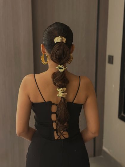 The full view of the accessorized ponytail, showing how it complements a sleek black dress.