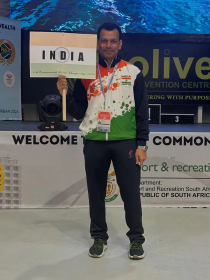 An Indian athlete proudly holding the country's nameplate at the Commonwealth Championship. We ensure our players represent Bharat with pride.