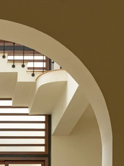 A detail of the curved staircase and archways in Casa 503. These architectural features create a sense of flow and openness, guiding light through the different levels of the home.