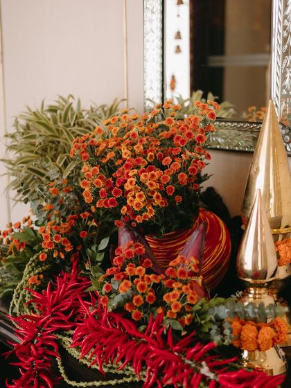 Vibrant floral arrangements for a Ganesh Pooja, using traditional colors of red and orange to create a warm and auspicious atmosphere for the pre-wedding rituals.