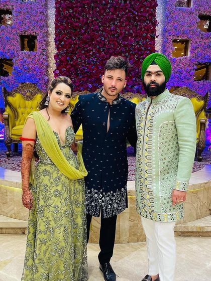 A guest in our navy blue embroidered bandhgala poses with the happy couple. The groom's friend wears a contrasting mint green sherwani, also from our collection.