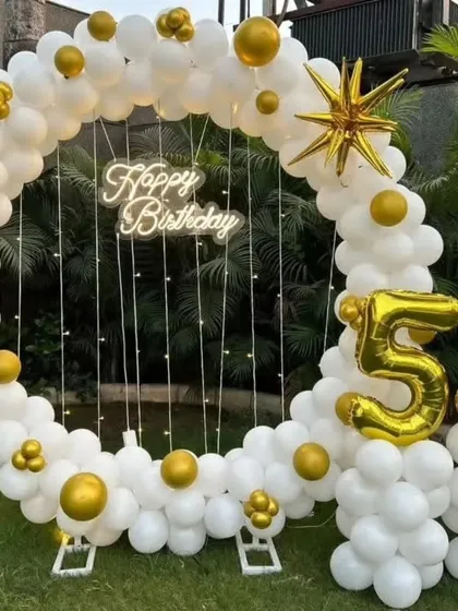 A classic white and gold theme for a 53rd birthday. This outdoor setup features a circular balloon arch, large foil numbers, and star-shaped accents.