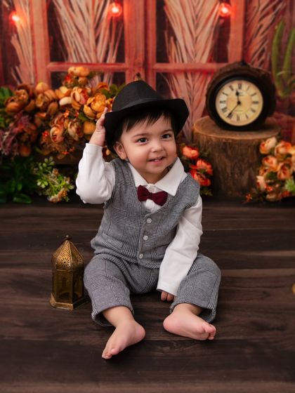 A dapper little gentleman in a rustic, vintage-themed setup. The warm lighting and classic props like the clock and lantern add a timeless feel.