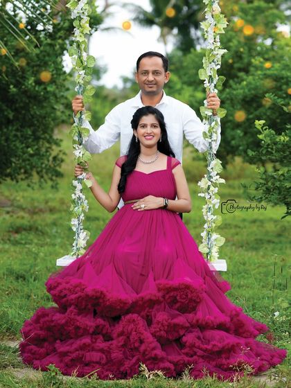 A classic couple's portrait on our floral swing. The mother-to-be is wearing a wine-colored ruffled gown.