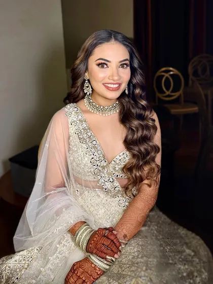 A smiling sangeet bride, looking absolutely flawless. Her makeup features a soft smokey eye and a natural lip, perfect for a long night of festivities.
