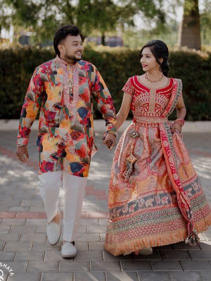 A happy walking shot of the couple in their vibrant and colorful Sangeet outfits.