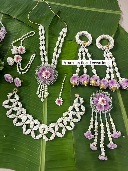A full baby shower jewellery set featuring purple and white flowers. This set includes a choker, long necklace, bajuband with kaleere, maang tikka, and a brooch.