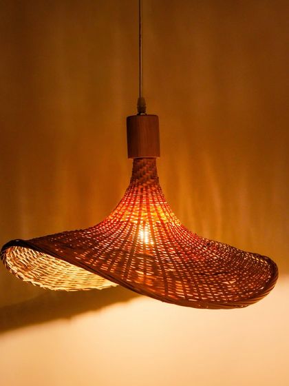 A unique, handwoven pendant lamp with a wide, sculptural shape. This piece is designed to be a statement fixture, adding a touch of organic texture and warm, ambient light to any room.