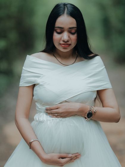 A serene solo portrait, with the mom-to-be looking down at her bump. The simple white gown is perfect for these quiet, reflective moments.