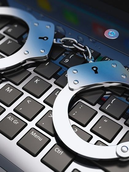 Handcuffs on a keyboard represent the real-world consequences of online criminal activity. As a cybercrime lawyer, I help bring digital criminals to justice.