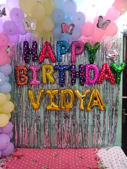 A close-up of the "Happy Birthday" foil balloons and butterfly cutouts.