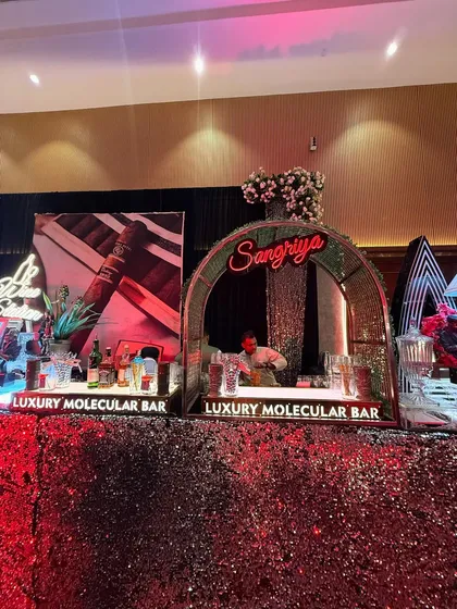 It's all in the details. This glamorous bar setup features a vibrant red sequin-paneled counter that catches the light beautifully, paired with a dedicated, neon-lit 'Sangriya' station to create an inviting and high-energy focal point.