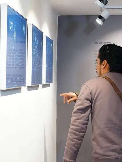 A moment of connection as one visitor points out a detail in a cyanotype print to another.