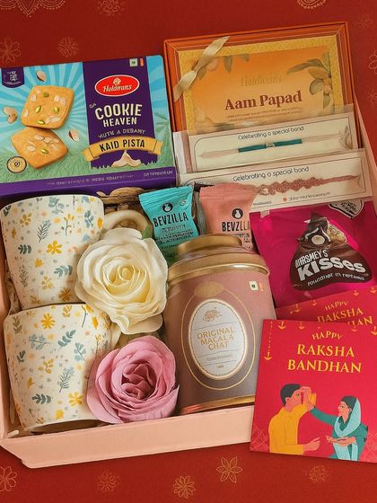 A delightful Rakhi hamper for your tea-loving Bhaiya and Bhabhi. It includes two floral coffee mugs, a cookie box, aam papad, masala chai, coffee cubes, and Hershey's Kisses.