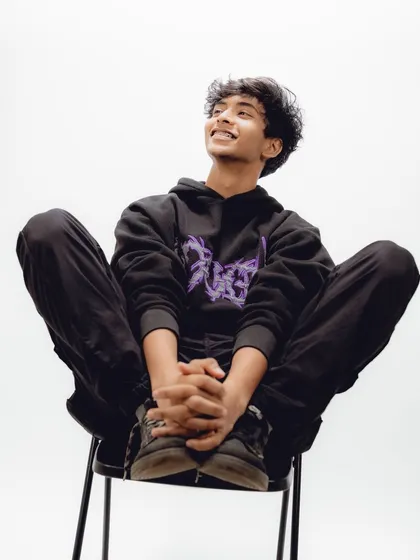 A candid, joyful moment from an artist's photoshoot, captured against a clean white backdrop.