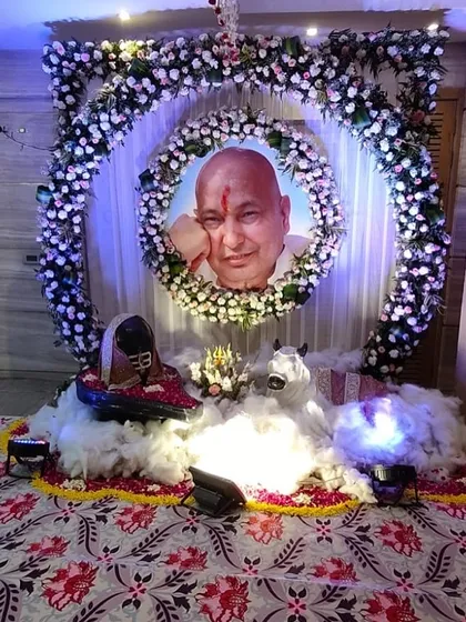 A unique and blessed setup for a Shiva pooja. Guru Ji's portrait is encircled by a ring of fresh white flowers, with a sacred Shivling and Nandi placed on a bed of soft cotton, representing Mount Kailash. This decoration focuses on creating a powerful spiritual ambiance.