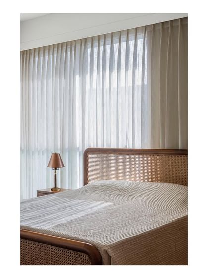 A bedroom designed to be a meditative and zen-like space. The custom bed features a caned headboard and a solid teak frame, with the entire room bathed in soft, natural light.