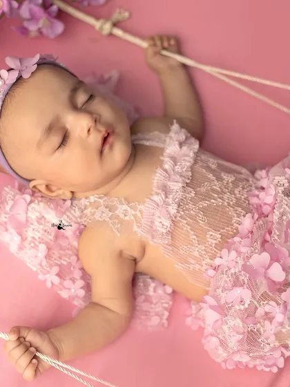 This newborn, dressed as a fairy, appears to be floating on a swing. The creative posing and props help bring a magical story to life.