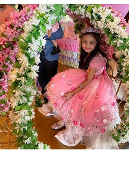 A princess in her floral castle. This beautiful off-the-shoulder pink gown is adorned with delicate 3D flowers and embroidery, making it a true fairytale dress for a special birthday celebration.