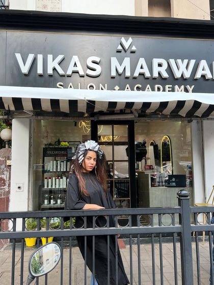 A fun shot of the client with foils in her hair, posing outside the salon before the final reveal. The transformation journey is always an exciting one.
