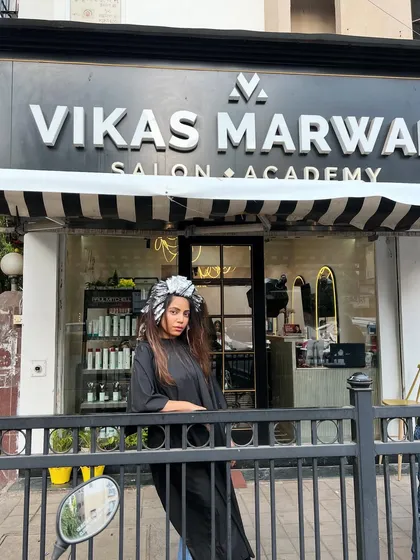 A fun shot of the client with foils in her hair, posing outside the salon before the final reveal. The transformation journey is always an exciting one.