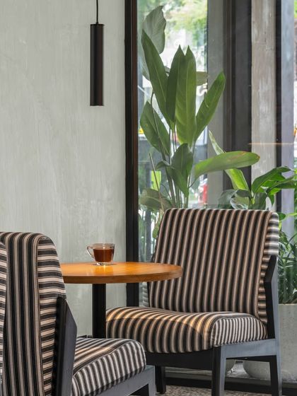 We love this soft, subtle palette of striped upholstery and warm wood against a concrete-finish wall. It holds its own character while celebrating Bangalore’s beautifully green outdoors, visible through the large window.