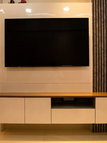The full view of the TV unit, showcasing the balance between the glossy white console, the textured wood paneling, and the artistic feather detail.