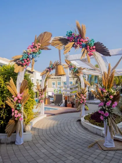 The entrance to a fun pre-wedding carnival, featuring a bohemian-style arch decorated with pampas grass and colorful flowers.