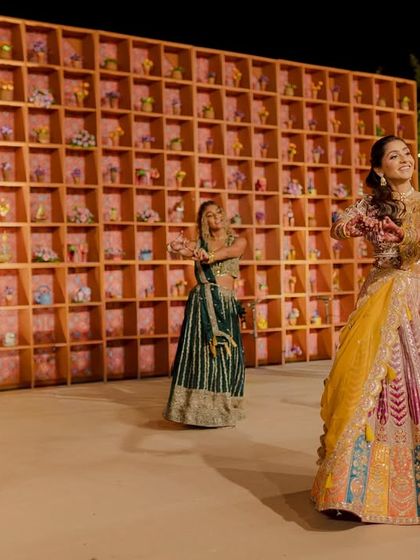 The bride and her bridesmaids perform at the Garba night. The backdrop is a custom-designed wall with hundreds of niches, each holding a small, unique floral arrangement.