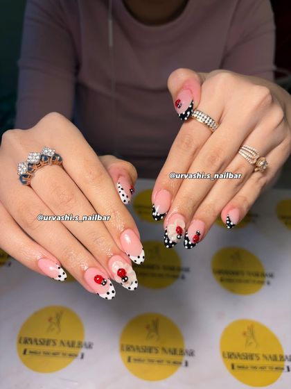 This cute and classy set features hand-painted polka dots and tiny ladybugs. The design uses a modern French tip style in black and white, with the playful bugs adding a whimsical touch.