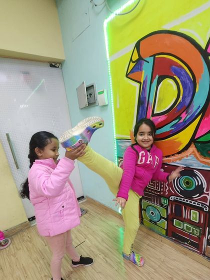 Stretching can be fun too. Our young dancers help each other with leg holds and kicks, building both flexibility and teamwork in the process.