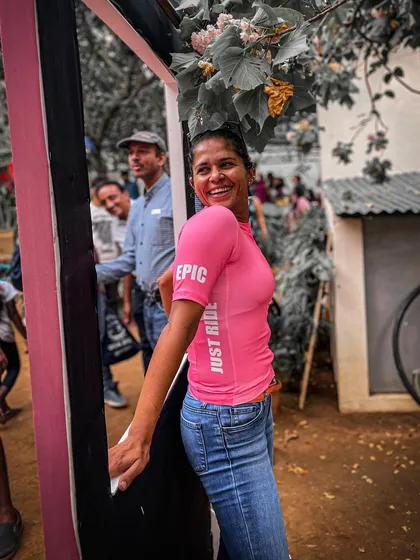 A candid moment from our Garage Sale. A member is seen smiling in our pink 'Just Ride' jersey, worn casually with jeans, showing the versatility of our apparel.