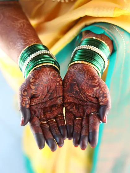 The rich, dark mehendi stain looks stunning paired with these traditional green glass bangles, perfect for any festive occasion.