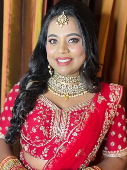 A close up of a reception look. The bride is wearing a red lehenga, and her makeup is classic and glamorous with a focus on defined eyes.